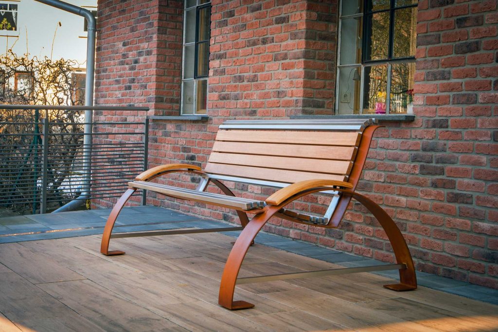 Auszubildendenprojekt von Mitarbeiter Louis Schüssler auf der Terrasse der alten Schmiede. Bank bestehend aus rostigem Cortenstahl, Edelstahl und Holz.