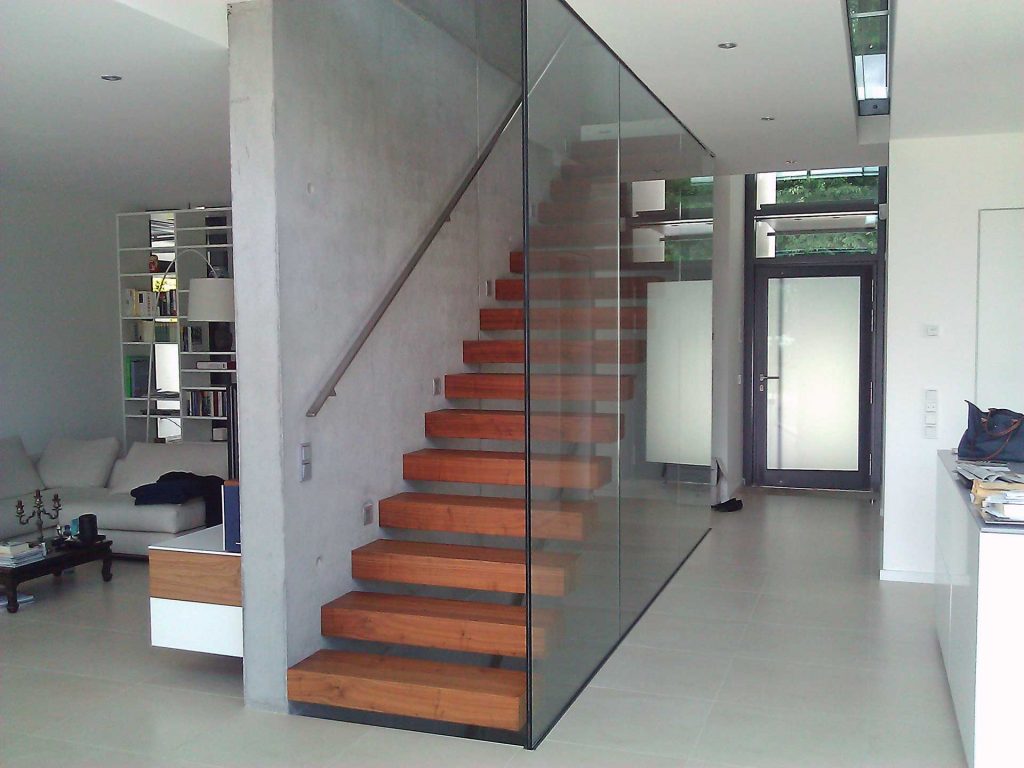 Kragarmtreppe mit unsichtbarer Unterkonstruktion. Mit Holzstufen und Edelstahlhandlauf an der Wand.