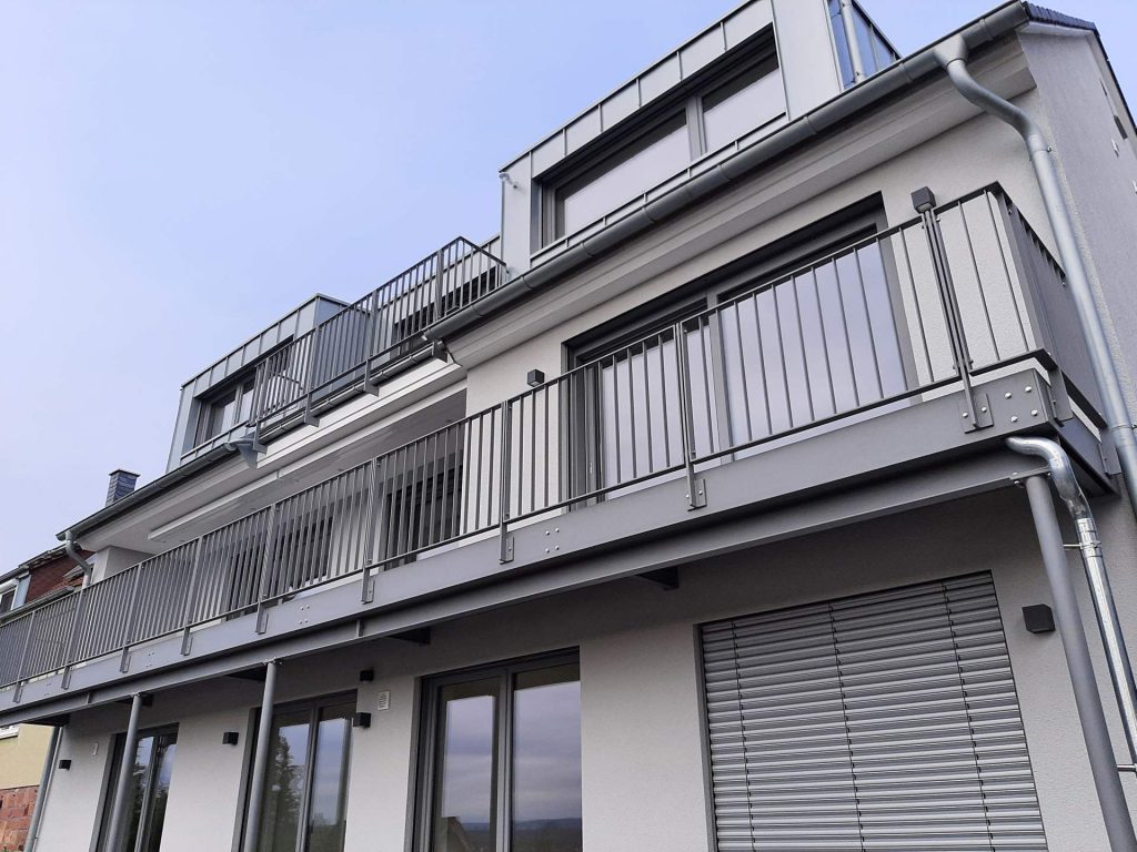 Stahlbalkon bestehend aus, aus Wand auskragenden IPE Profilen auf Unterzug auf 4 Stützen. Balkonbelag aus Fundermax Platten Wasserdicht mit Flachstahlgeländer. alle Stahlteile feuerverzinkt und pulverbeschichtet