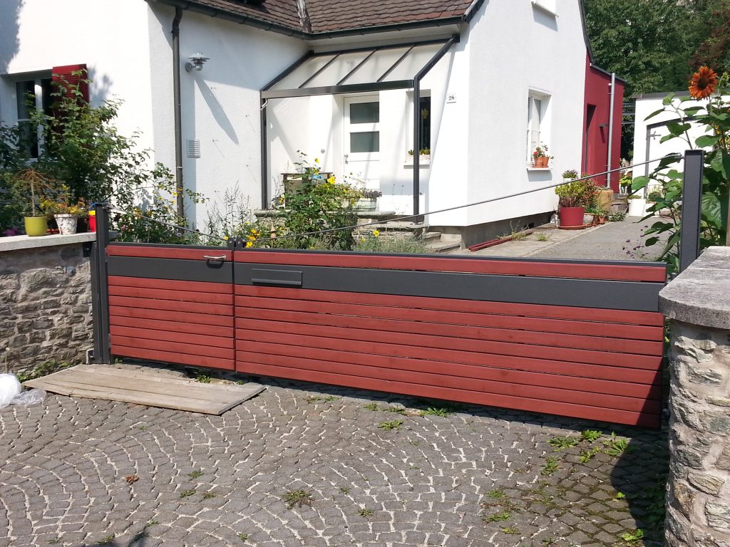 2-flügliges Hoftor mit kleinem Gehflügel als Fußgängerdurchgang, mit roten Holzbrettern beschlagen