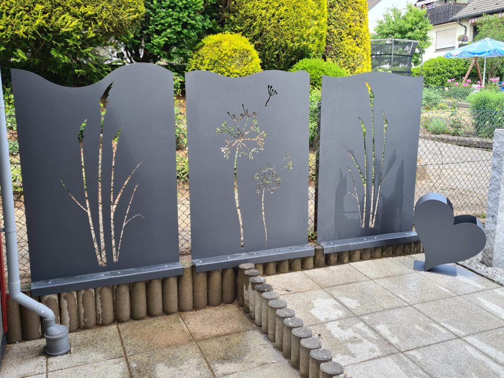 Raumtrenner/Sichtschutz aus Blechen mit Ausschnitten nach Kundenwunsch als Pusteblumen und Gräsern. Mit Blumentopf in Herzform. Alle Blechteile sind anthrazit Pulverbeschichtet.