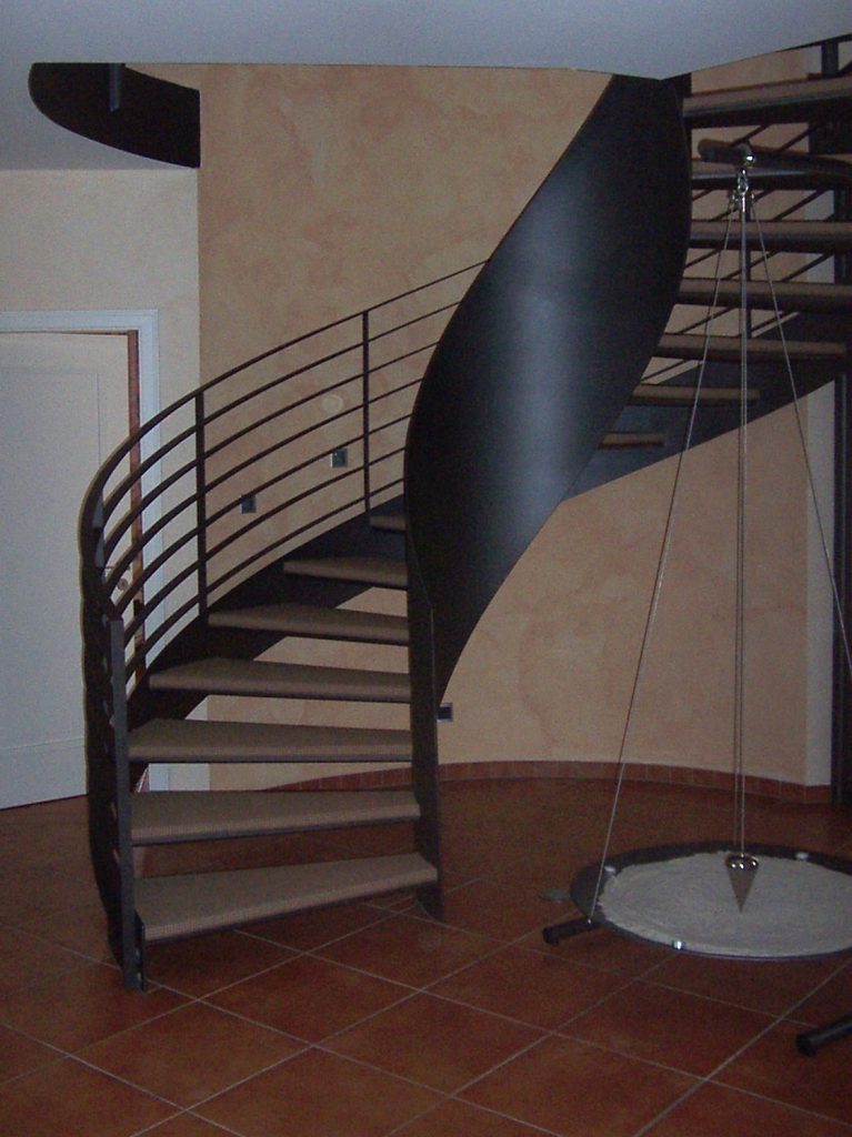 Wendeltreppe aus rund gewalztem Stahlblech mit Geländer aus gewendelten Flachstählen und eingeschweißten Stufenwannen ebenfalls aus Stahlblech, verfüllt mit Gussasphalt und mit Sisalteppich belegt. Stahlteile sind Lackiert im Farbton Anthrazit "Eisenglimmer"