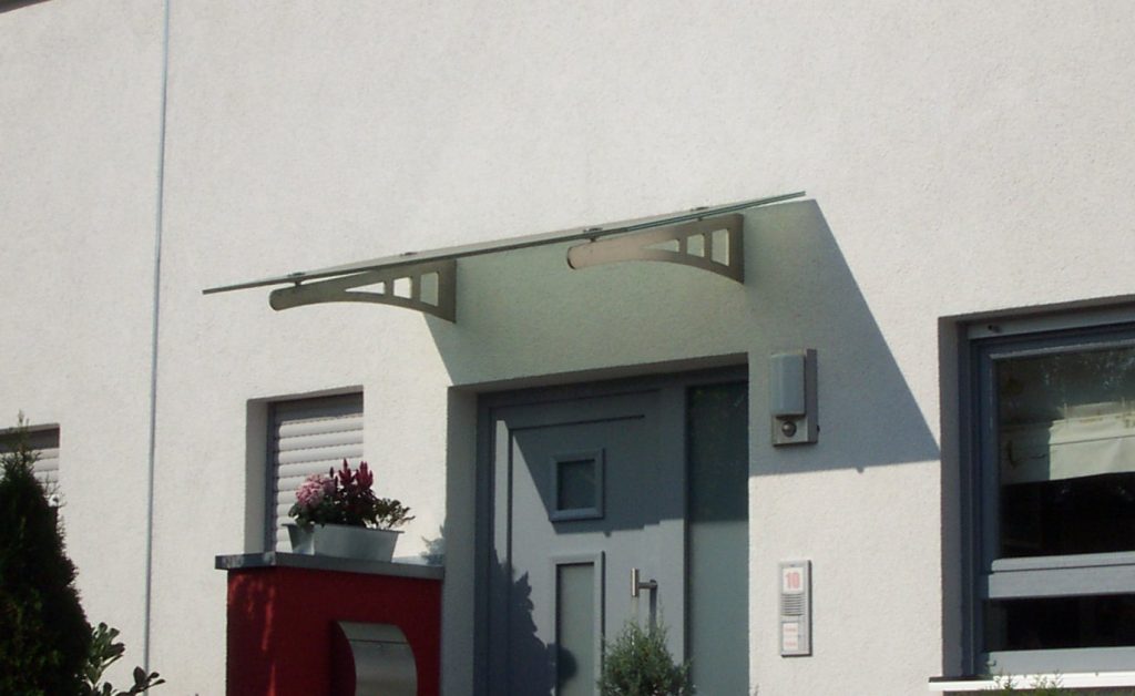 Vordach aus an Wand befestigter Edelstahlkragarme mit Glasscheibe belegt